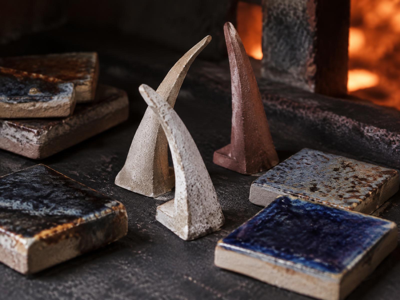 Pyrometric cones and cobalt test tiles arranged on a dark kiln shelf